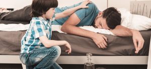 A Child Tries To Wake Up An Alcohol Addicted Parent.