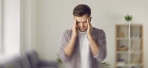 Young Man Holding Head In Distress From Potential Delirium Tremens And Alcohol Addiction.